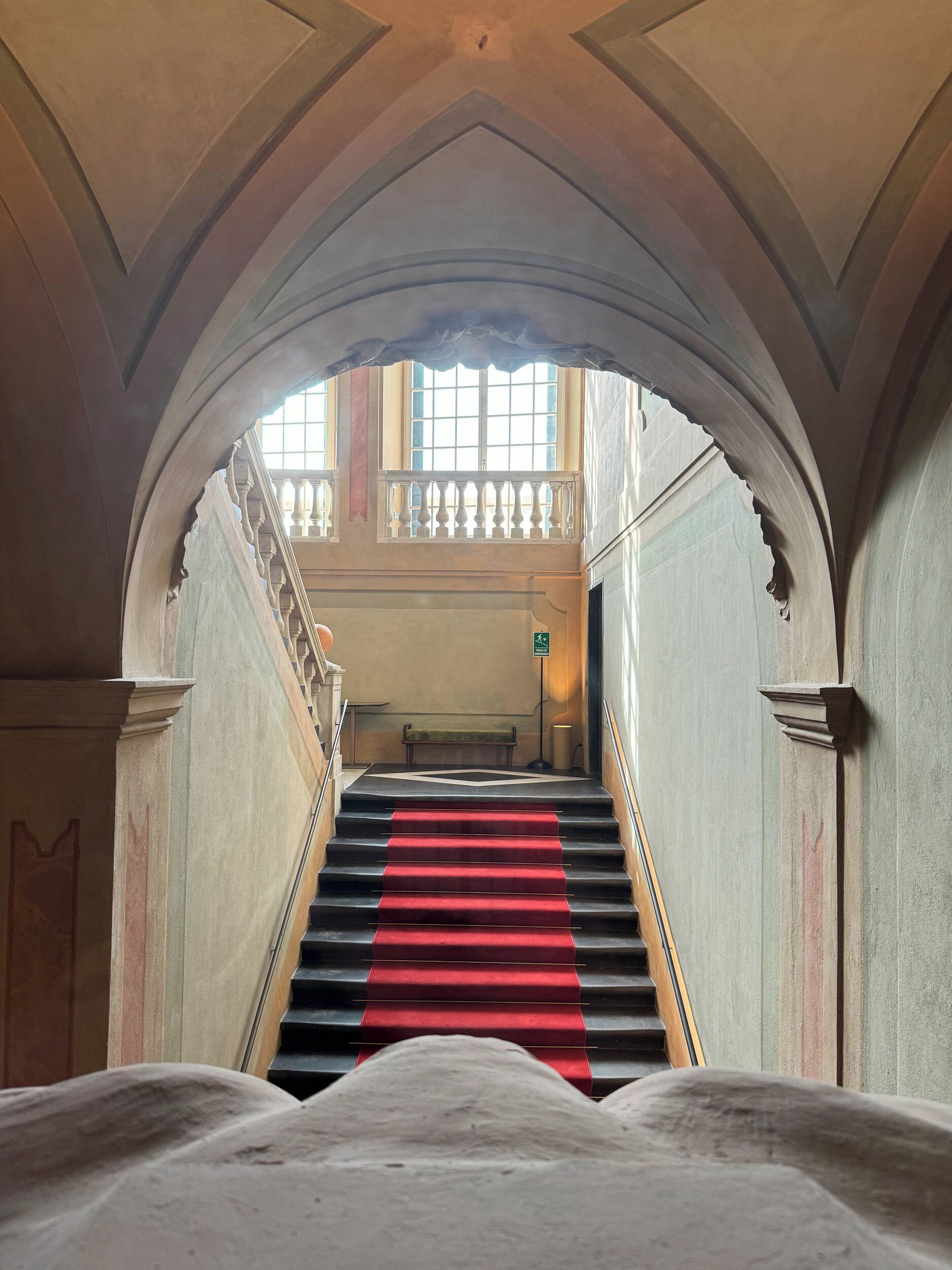 A grand staircase with a red carpet leading to a balcony.