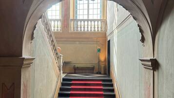 A grand staircase with a red carpet leading to a balcony.