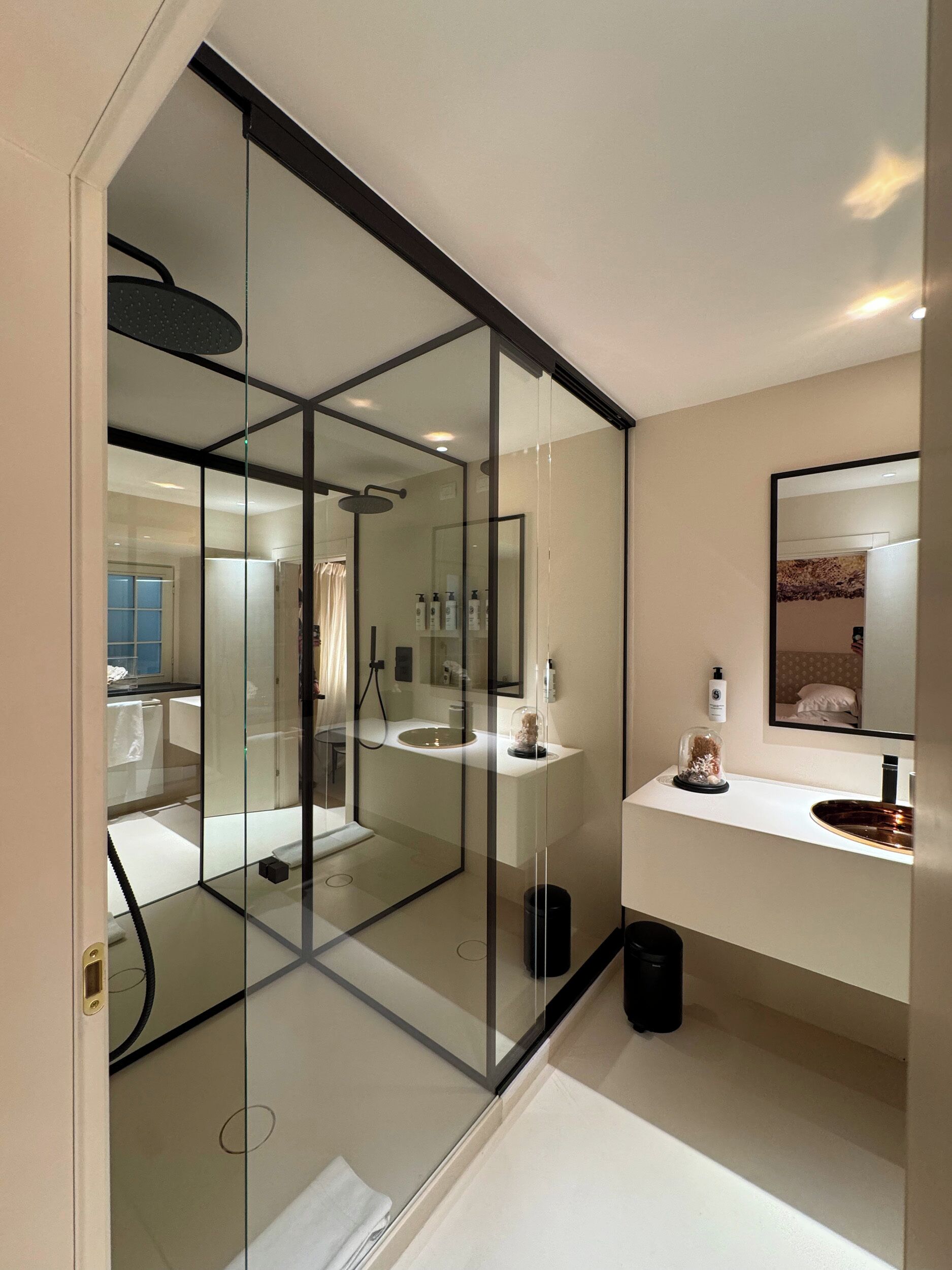 Ein modernes Badezimmer mit Glastrennwand, Waschbecken, Spiegel und Duschbereich.