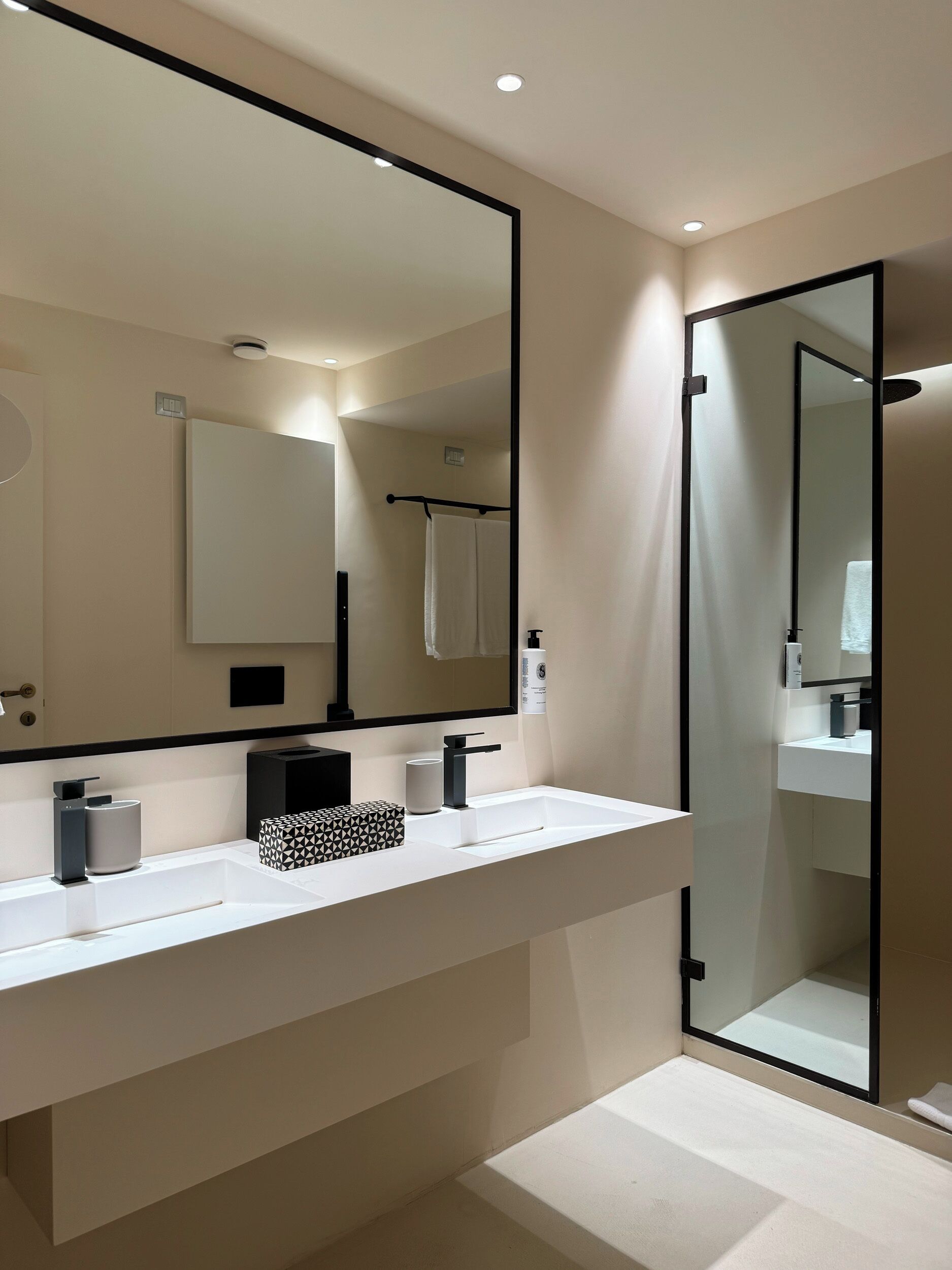 A modern bathroom with a large mirror, a white sink, and a glass shower enclosure.