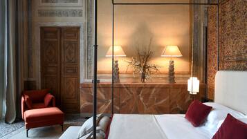 A hotel room with a bed, a chair, a nightstand with lamps, and a decorative wall.