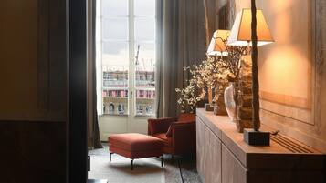 Una habitación de hotel con un ventanal grande, una silla roja, una lámpara y un florero decorativo.