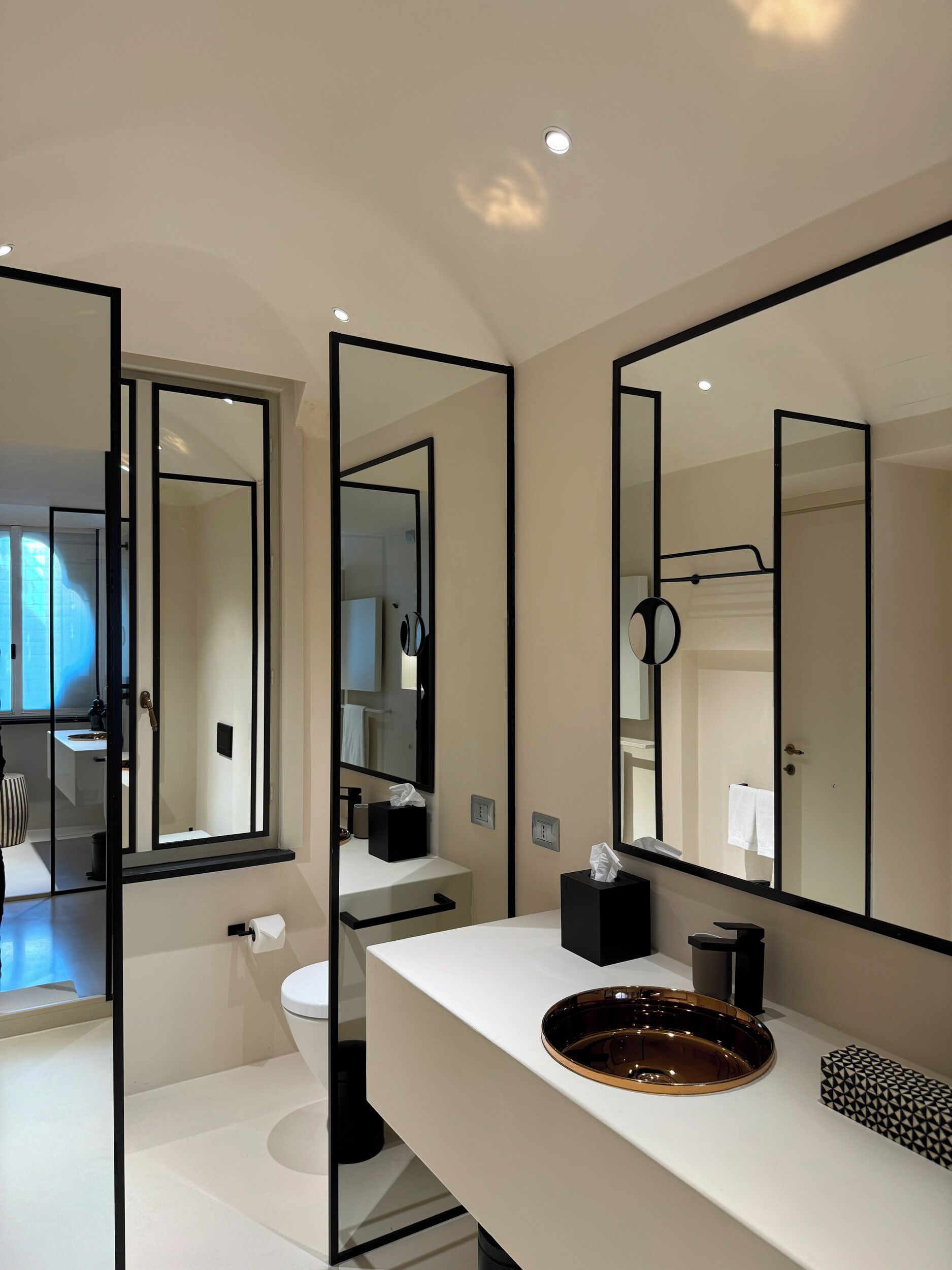 A modern bathroom with a white sink, a round mirror, and a toilet.