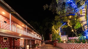 A building with a brick facade, multiple balconies, and a paved walkway. - Itsy Hotels Sun N Shade (Karjat)