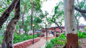 A pathway leading to a building with a brick facade, surrounded by lush greenery and trees. - Itsy Hotels Sun N Shade (Karjat)