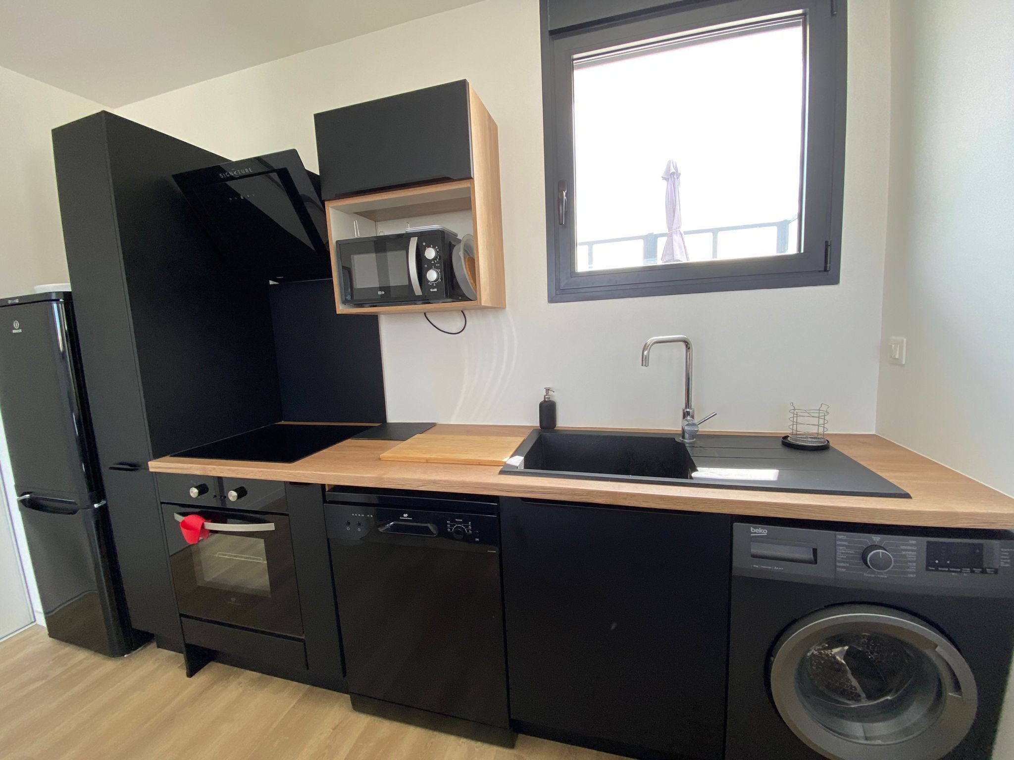 A compact kitchen with a dishwasher, oven, microwave, and a built-in washing machine.