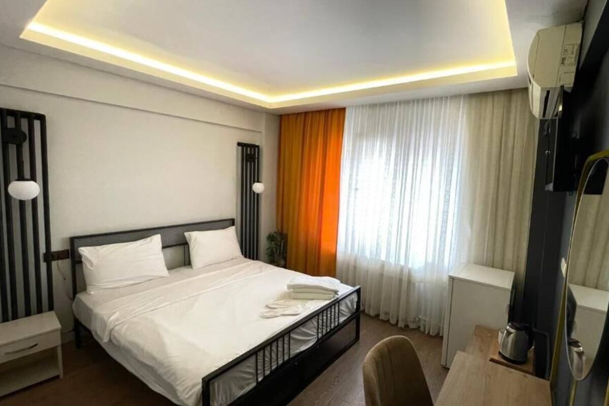 A hotel room with a bed, bedside table, chair, and a mirror.