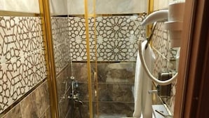 Un bagno con un lavandino grande e rotondo, un box doccia in vetro e piastrelle decorate.