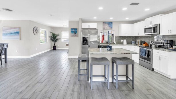Una cocina moderna con armarios blancos, electrodomésticos de acero inoxidable y encimera gris.
