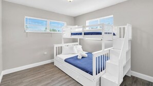 Una habitación con una cama litera, una ventana con persianas y una lámpara de techo.
