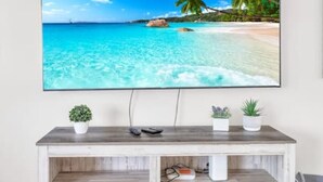 Un televisor de pantalla plana montado sobre un mueble de madera con tres macetas.