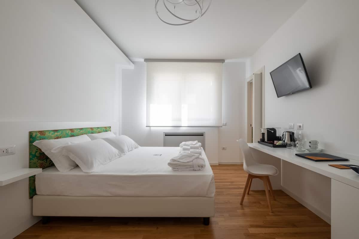 A modern bedroom with a bed, a desk, and a TV.