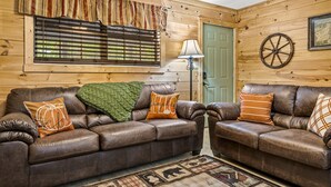 A cozy room with two leather sofas, a green door, a lamp, and a wooden wall with a map. - Quiet Cove 3 bdrm cabin/Smoky Mountains/Ober Gatlinburg (Gatlinburg)