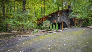 A rustic cabin with a wooden exterior, a covered outdoor area, and a gravel driveway surrounded by trees. - Quiet Cove 3 bdrm cabin/Smoky Mountains/Ober Gatlinburg (Gatlinburg)