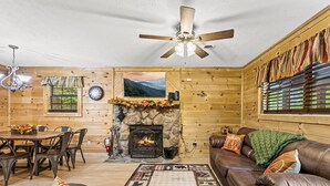 A cozy log cabin interior with a fireplace, wooden walls, a dining area, and a leather couch. - Quiet Cove 3 bdrm cabin/Smoky Mountains/Ober Gatlinburg (Gatlinburg)