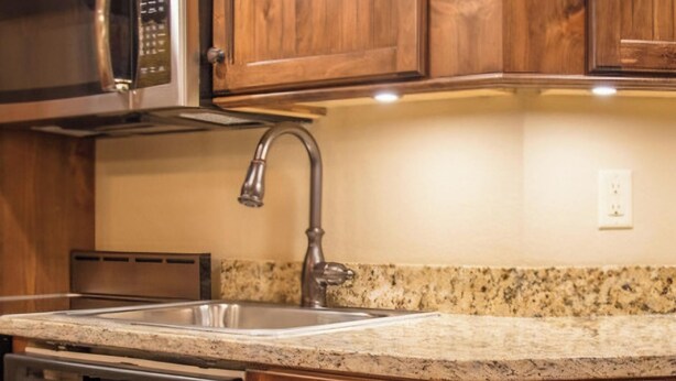A kitchen with wooden cabinets, a stainless steel microwave, a dishwasher, and a granite countertop. - Westgate Resort with beautiful mountain views, Smoky Mountain National Park (Gatlinburg)