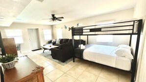 A compact hotel room with a bunk bed, a sofa, a small table, and a ceiling fan. - FREE Heated Pool, Weber Gas Grill, 3 miles to the beach! (West Palm Beach)