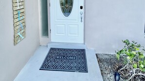 A white door with a glass panel, a welcome mat, a 'Welcome' sign, and a 'Whalecome' sign on the wall. - FREE Heated Pool, Weber Gas Grill, 3 miles to the beach! (West Palm Beach)