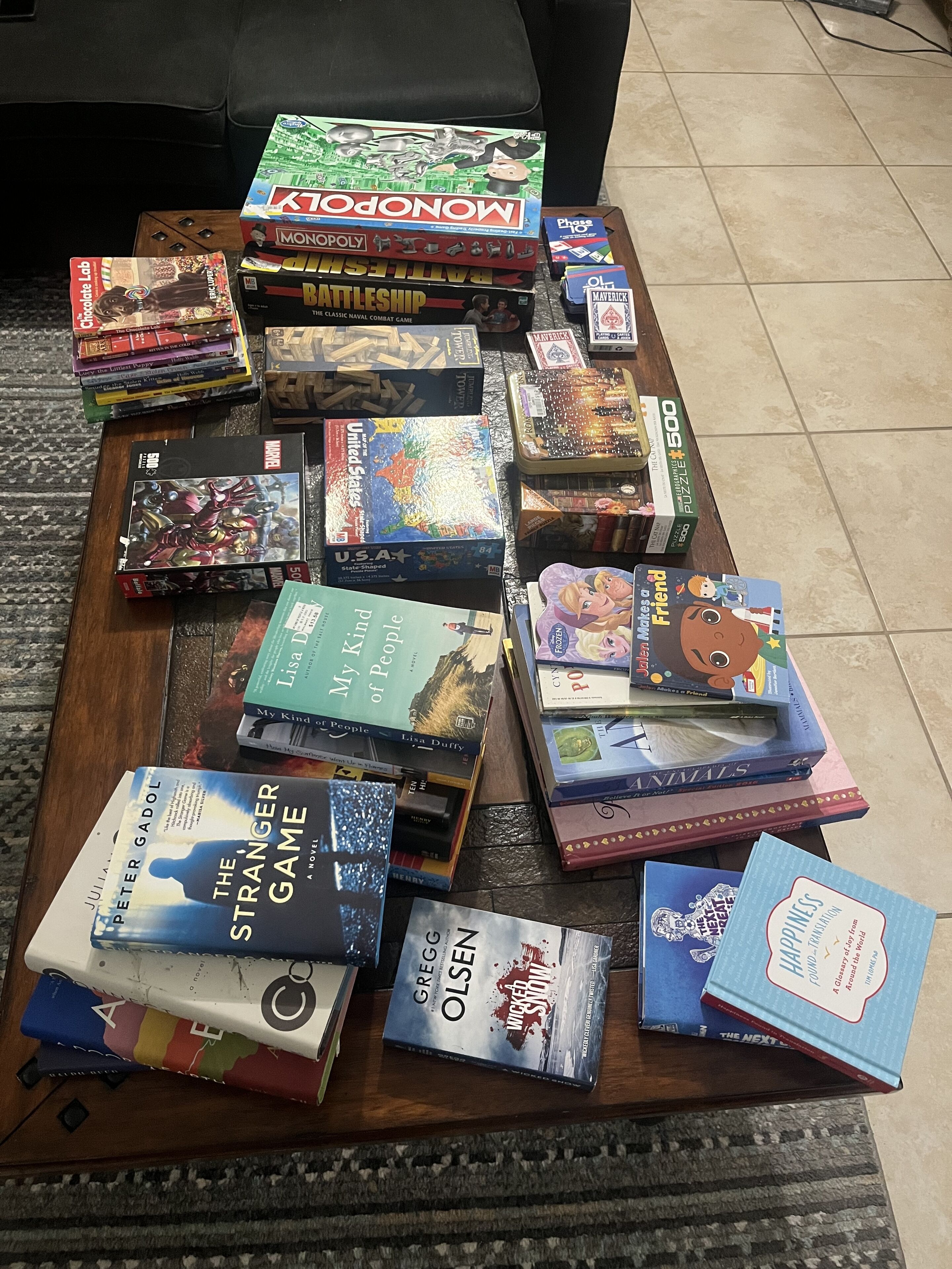Une variété de jeux de société et de livres disposés sur une table basse en bois.