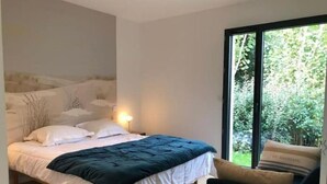 A bedroom with a bed, a nightstand, a lamp, and a window with a view of greenery. - Villa Tixaya 5*, a cosy cocoon to recharge your batteries by the lake and ocean (Gastes)