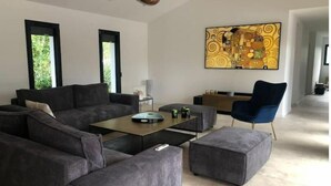 A modern living room with a sectional sofa, a coffee table, and a blue armchair. - Villa Tixaya 5*, a cosy cocoon to recharge your batteries by the lake and ocean (Gastes)