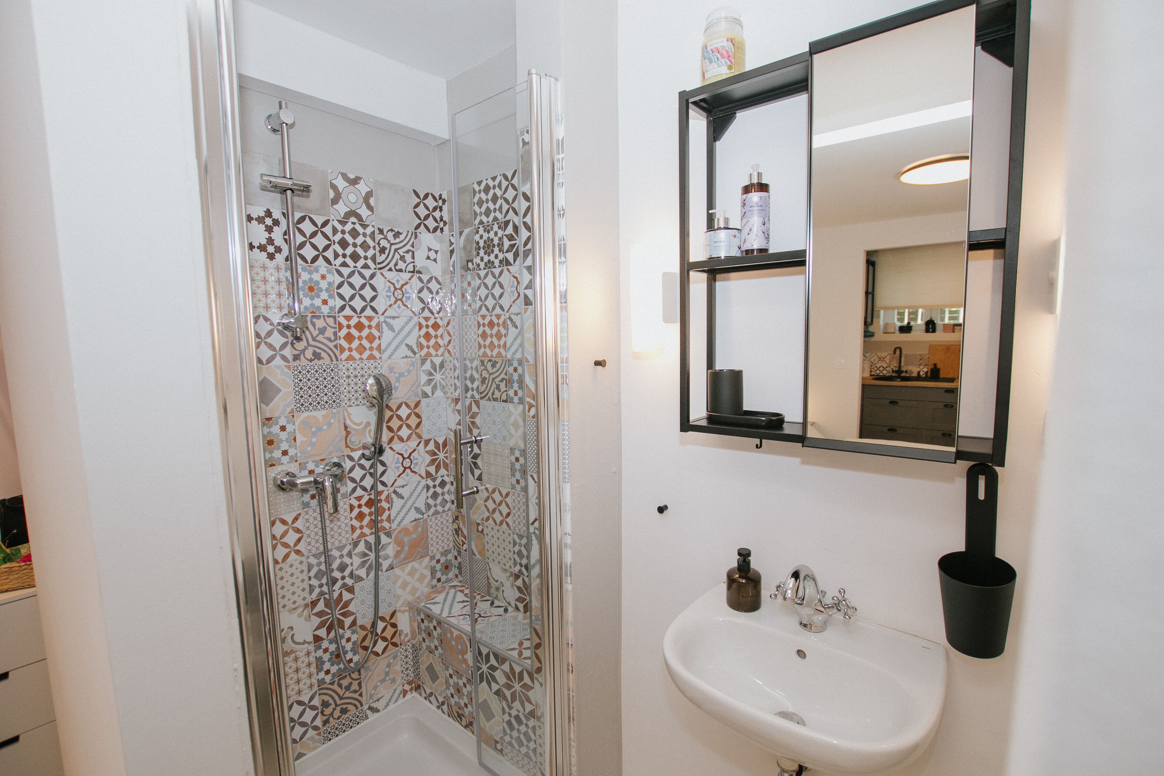 Un baño con ducha, lavabo y espejo.
