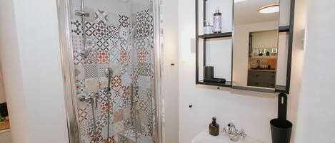 Un baño con ducha, lavabo y espejo.