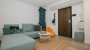 A modern living room with a sectional sofa, a round coffee table, a decorative blue cabinet, and a wooden door. - First love Apartment in Zagreb center (Zagreb)
