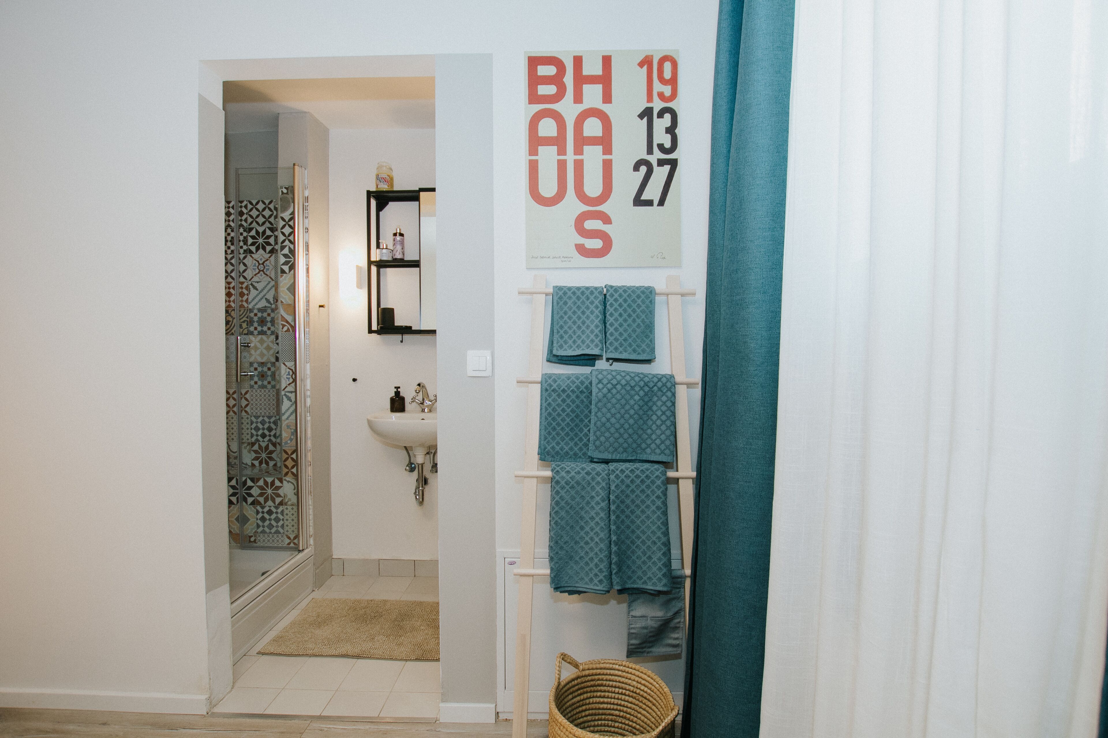 A bathroom with a shower, sink, and towel rack.