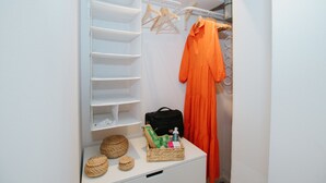 A neatly organized closet with hanging space, shelves, and a small table with baskets and a bag. - First love Apartment in Zagreb center (Zagreb)