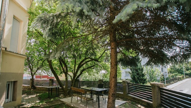 An outdoor patio with a table and benches, surrounded by trees and a fence. - First love Apartment in Zagreb center (Zagreb)