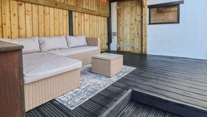 A wooden deck with a sofa and ottoman, a wooden wall, and a door. - 18 Church Street (Llangollen)