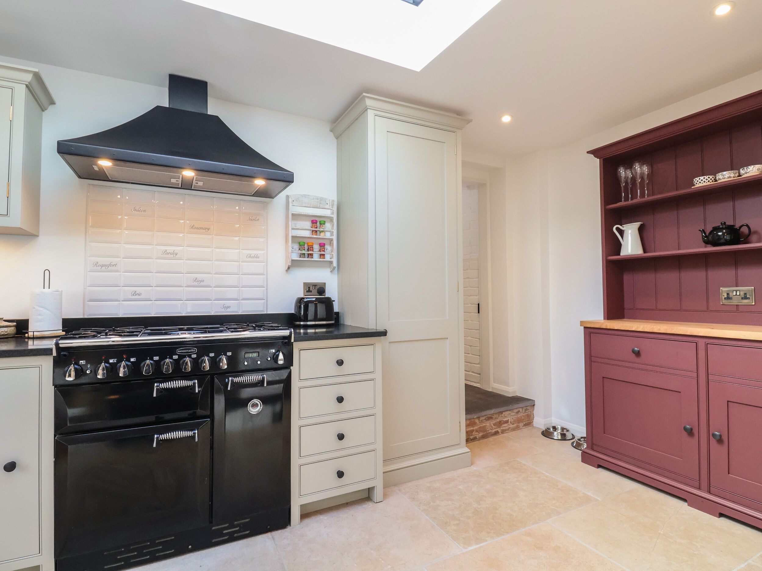 A kitchen with a gas stove, a black range hood, and a white backsplash with labels.