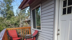 Eine Holzterrasse mit zwei Korbstühlen und einem kleinen Tisch.