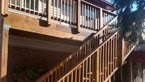 Eine Holztreppe führt zu einem Balkon mit einem roten Dach.