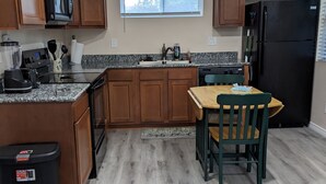 Eine Küche mit Holdekor, einer Arbeitsplatte aus Granit, einem schwarzen Kühlschrank und einem Essbereich mit Holztisch und Stühlen.