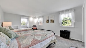 Un dormitorio con dos camas, una silla, una lámpara y una chimenea.