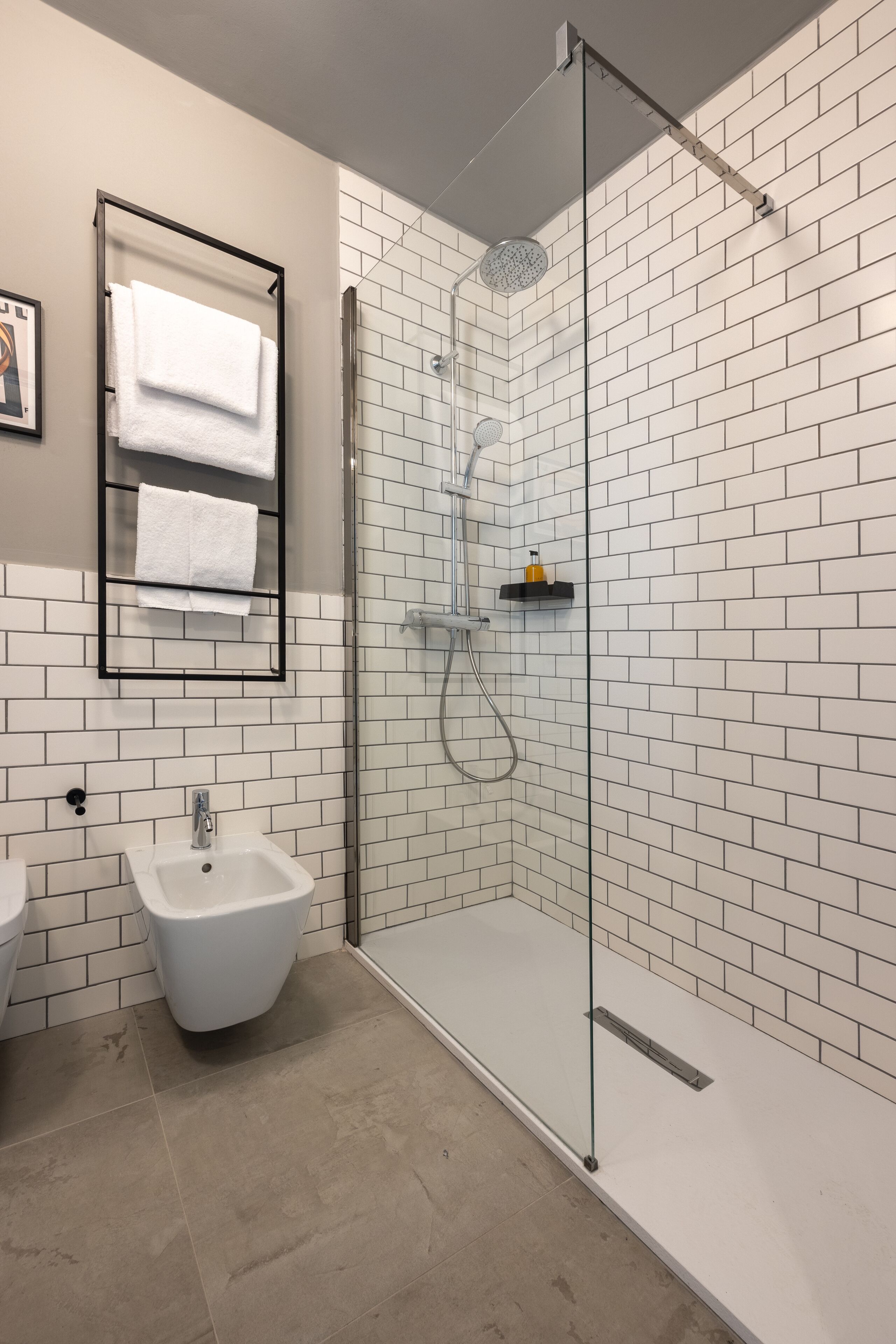 Un baño moderno con ducha de vidrio, lavamanos blanco y bidé.