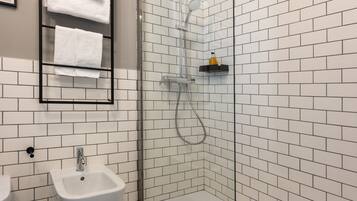A modern bathroom with a glass-enclosed shower, a white sink, and a bidet.