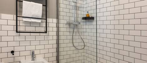 Un baño moderno con ducha de vidrio, lavamanos blanco y bidé.