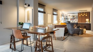 Una sala de estar moderna con una mesa de comedor de madera, asientos cómodos y una cocina al fondo.