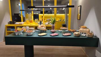 Un bufé de desayuno con diversas opciones de comida y un mostrador amarillo al fondo.