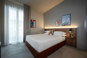 Camera d'albergo moderna con un letto grande, un comodino con una lampada e opere d'arte alle pareti.