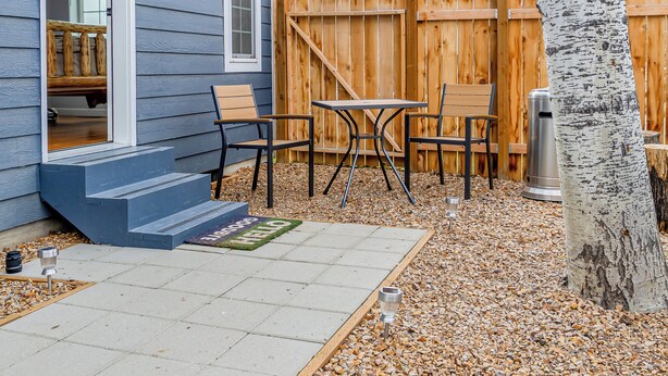 A house with a patio area featuring a table and chairs, a wooden deck, and a tree. - Cozy Queen, Private Bathroom and Entryway (Bend)