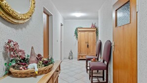Un couloir avec une armoire en bois, un miroir et un panier en osier contenant des objets décoratifs.