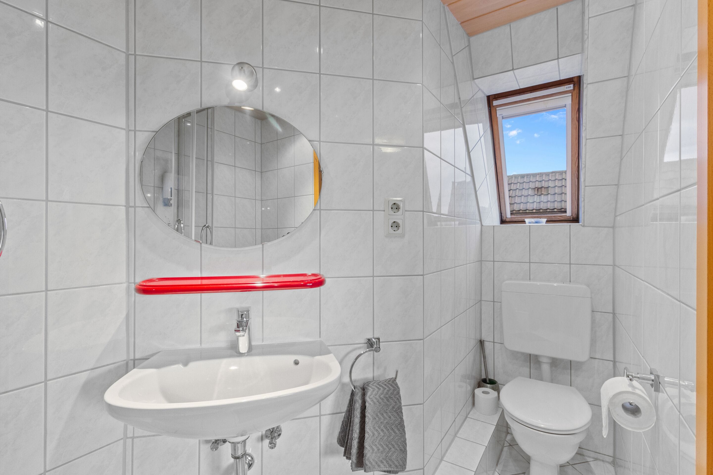 A modern bathroom with a white sink, mirror, and toilet.