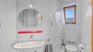 A modern bathroom with a white sink, mirror, and toilet.