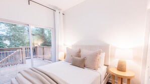 A bedroom with a large bed, a nightstand, a lamp, and a view of a balcony. - Chic & Cozy Home Near UK Campus! Perfect for Family Visits. (Lexington)
