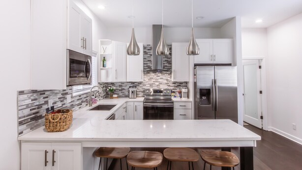 A modern kitchen with white cabinetry, stainless steel appliances, a marble island, and hanging pendant lights. - Chic & Cozy Home Near UK Campus! Perfect for Family Visits. (Lexington)
