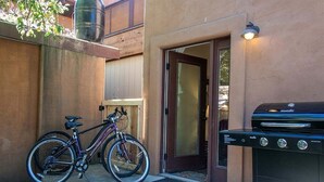 A bicycle parked next to a wooden door and a barbecue grill outside a building. - Bluebird Day - Casa Sol: Cozy 2BR townhome in Bend, OR, featuring two King beds and a hot tub. (Bend)